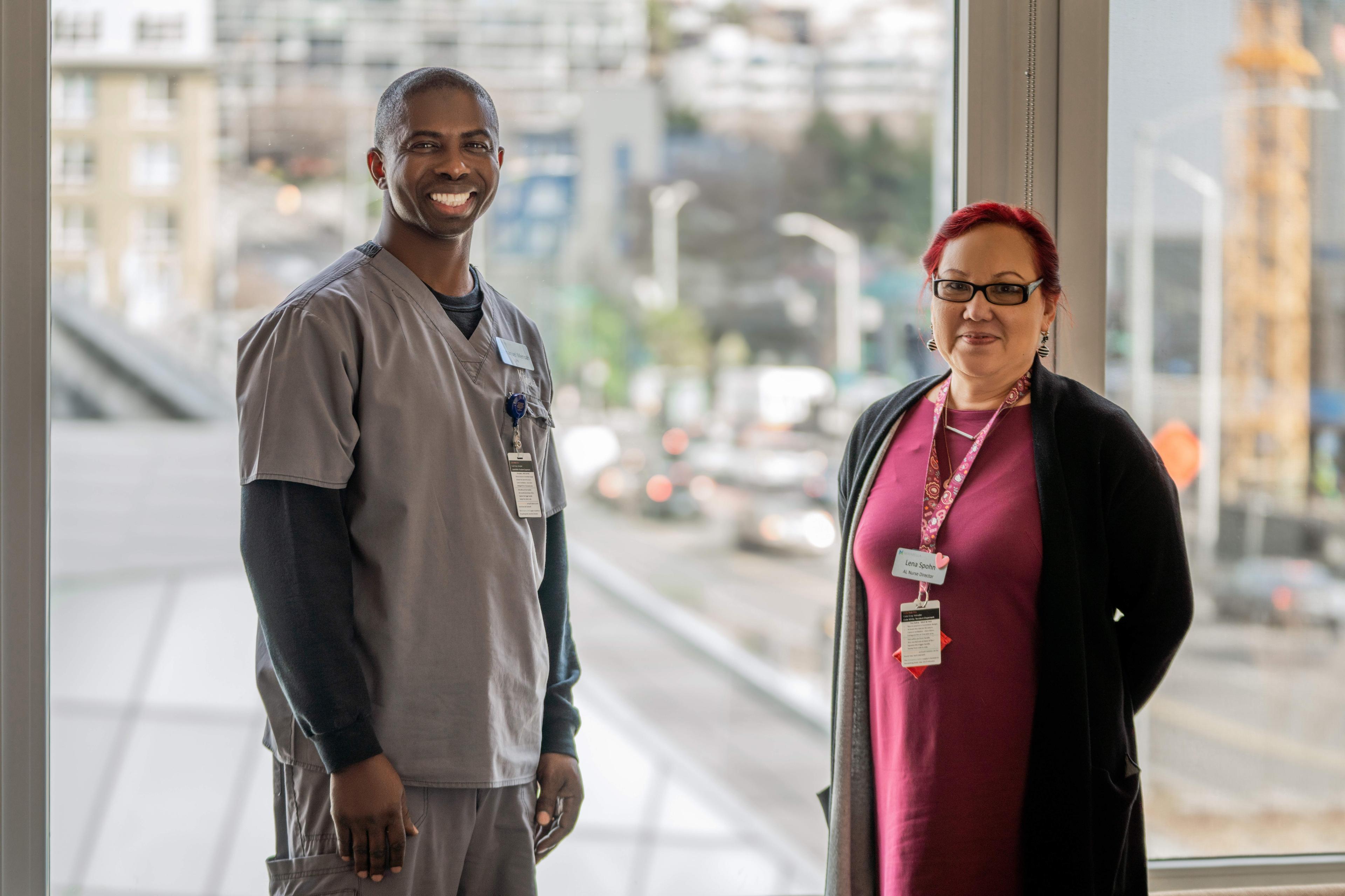 Two smiling Mirabella healthcare employees stand in front of a window.