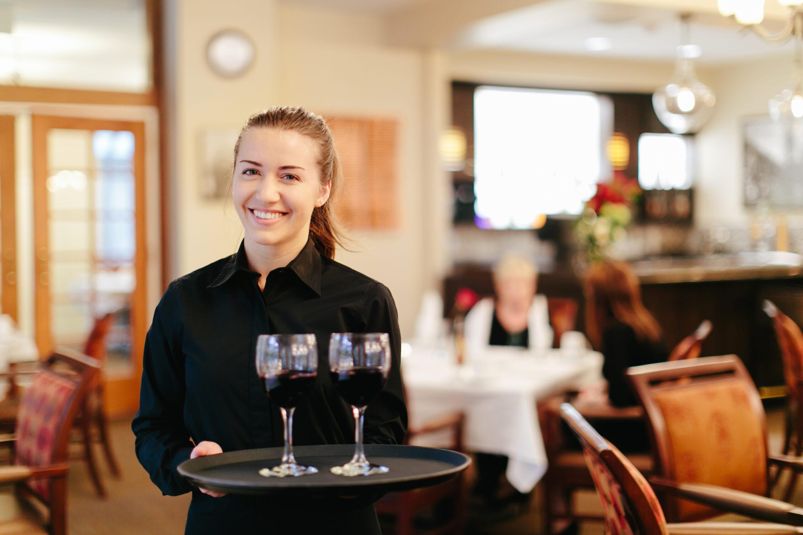A server holds two glasses of wine.